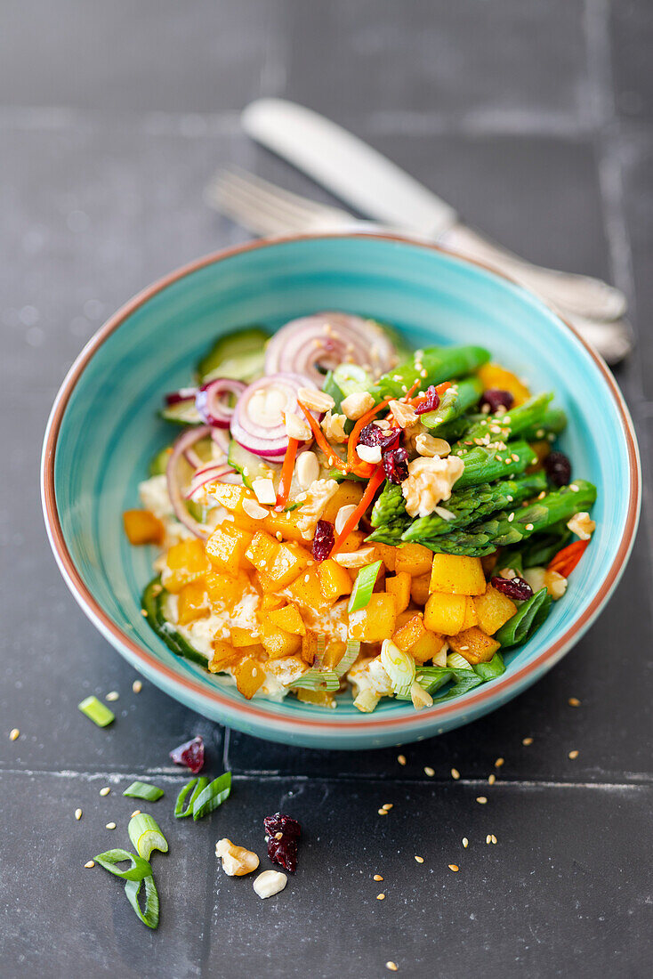 Bowl with sweet potatoes, feta cream, cucumber salad, green asparagus and red onion