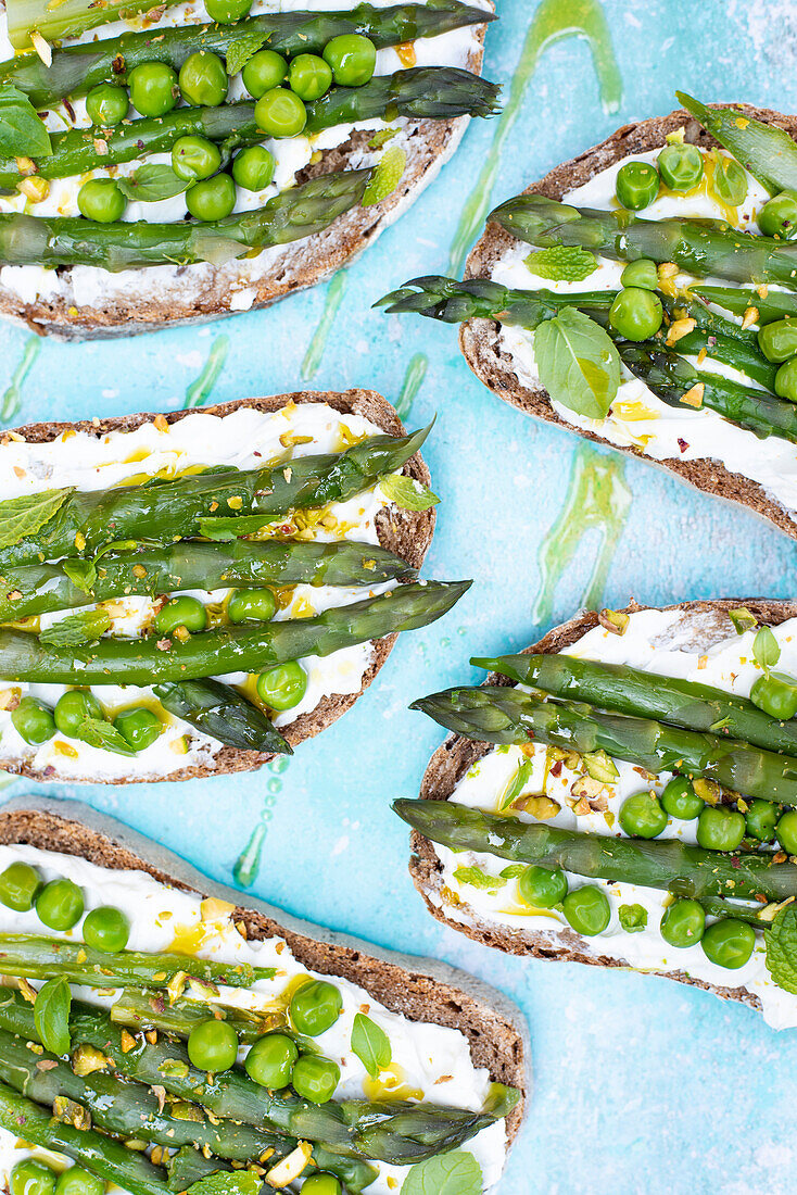 Bread slices with goat cheese, green peas and asparagus