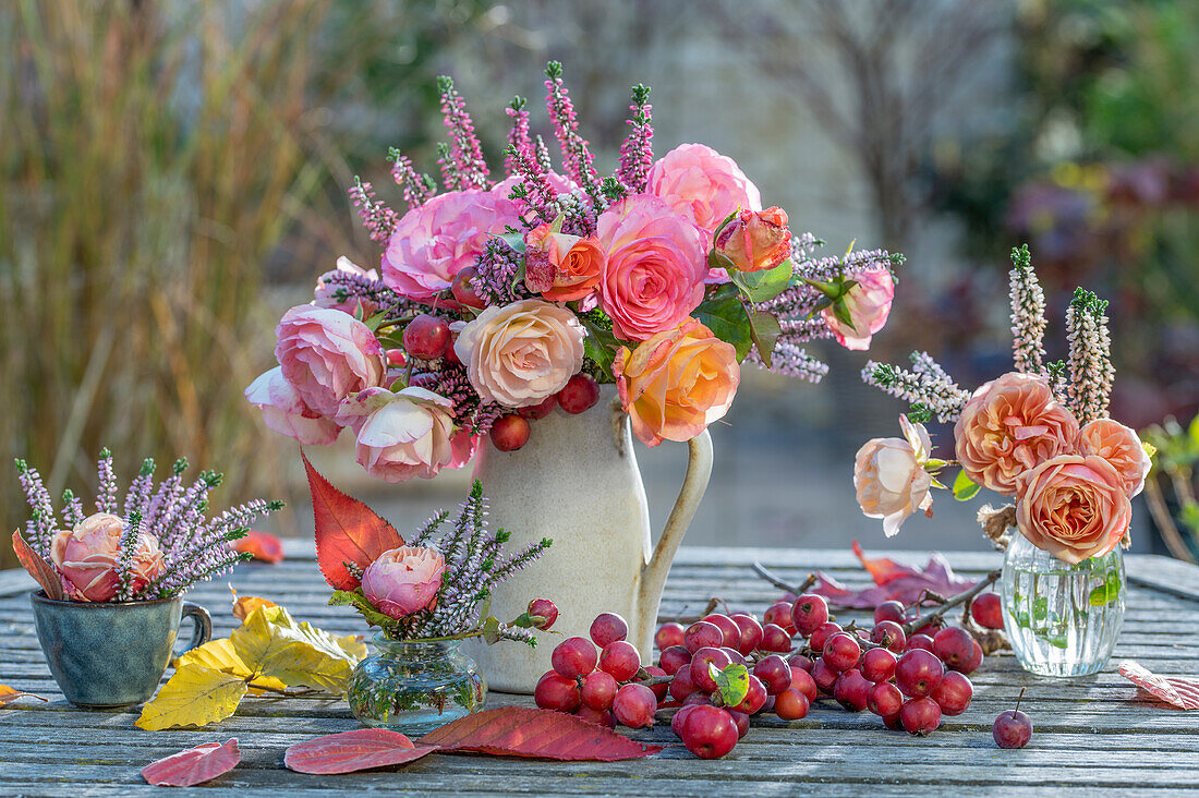 Herbstliche Tischdeko aus Rosenstrauß (Rosa), Besenheide (Calluna vulgaris) und Zierapfel