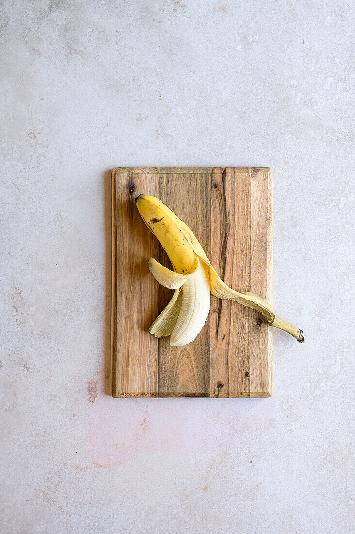Half peeled banana on a cutting board