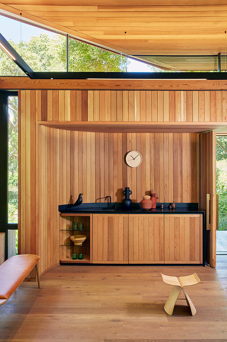 Modern kitchen unit with wood paneling and black countertop