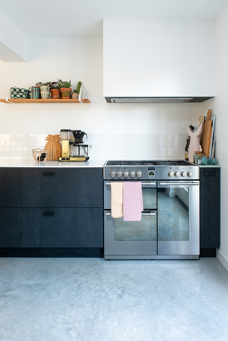 Moderne Küchenzeile mit dunkler Schrankfront, Edelstahlgeräten und Holzregal