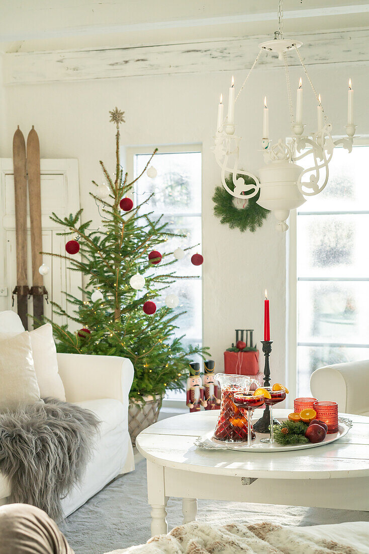 Weihnachtlich geschmücktes Wohnzimmer mit Tannenbaum und Punschgetränk auf dem Tisch