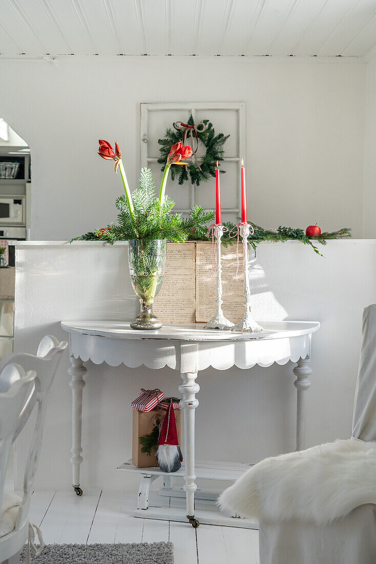 White console table decorated for Christmas with amaryllis and candles