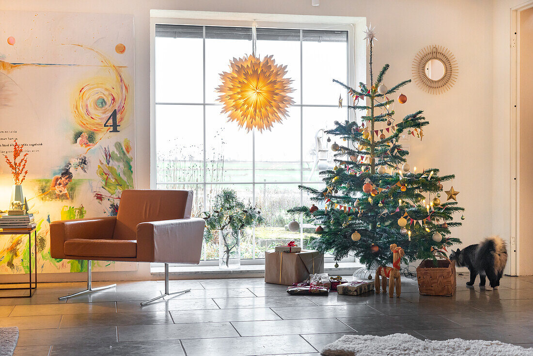 Wohnzimmer mit Weihnachtsbaum und Sessel vor Fenster