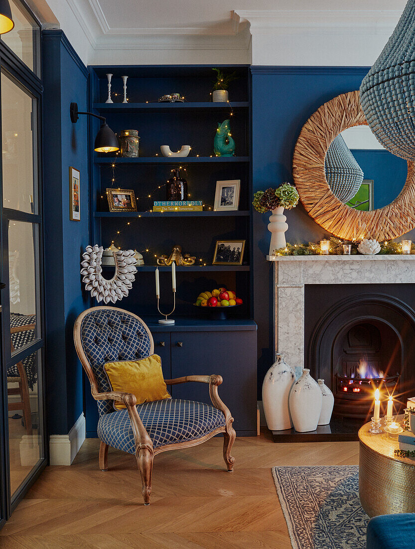 Open shelves next to fireplace in living room with blue walls and Christmas decorations