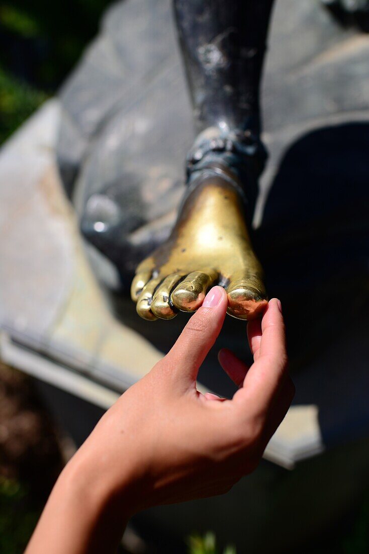 Tourist touching statue?s feet at The Achilleion Palace in Village of Gastouri (Sisi's beloved Greek summer palace), Corfu, Greece