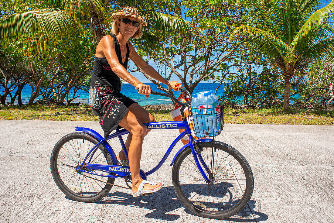 Touristenmädchen mit einem Fahrrad in Fakarava, Tuamotus-Archipel, Französisch-Polynesien, Tuamotu-Inseln, Südpazifik.