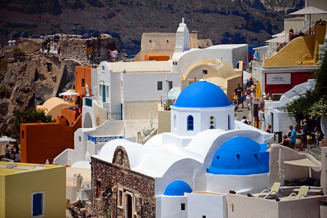 Hillside buildings with traditional church blue domes in Oia, Santorini, Greek Islands, Greece