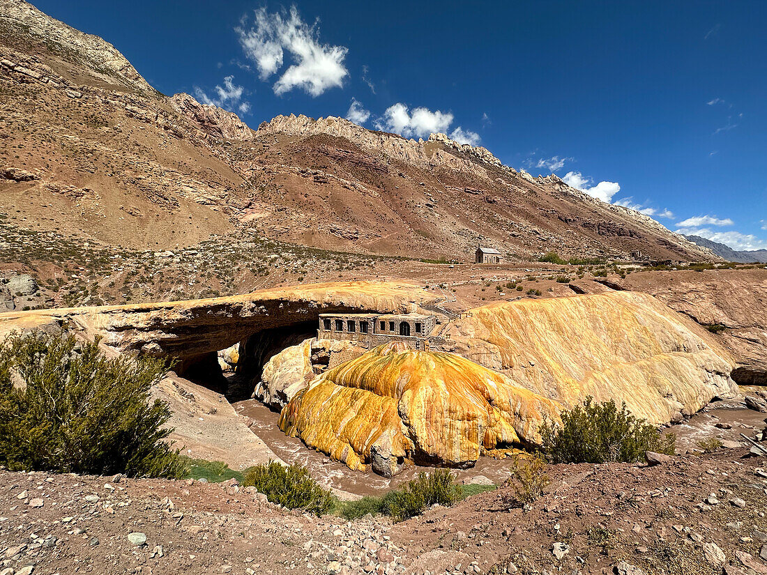 Colorful travertine deposits of the mineral spring at Puente del Inca in the Andes Mountains of Argentina, with the ruins of a former spa.