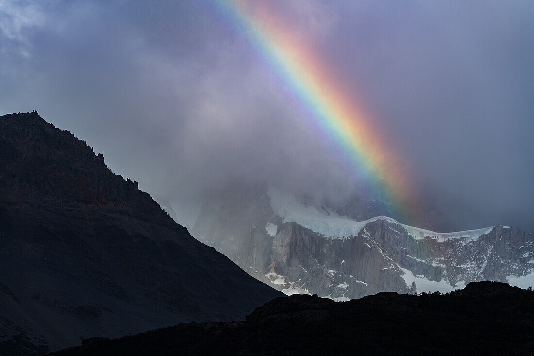 Ein Regenbogen auf den Wolken, die den Berg Fitz Roy im Nationalpark Los Glaciares bei El Chalten, Argentinien, einhüllen. Eine UNESCO-Welterbestätte in der Region Patagonien in Südamerika.