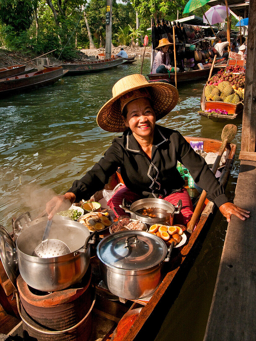Frau, die auf dem schwimmenden Markt von Damnoen Saduak in Ratchaburi, Thailand, Lebensmittel von einem Boot aus verkauft.