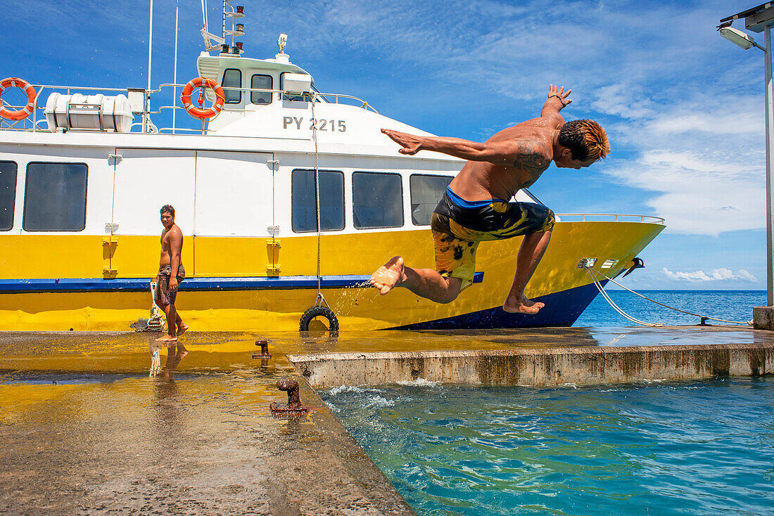Jugendliche springen ins Wasser neben der Anlegestelle von Bora Bora Vaitape, Gesellschaftsinseln, Französisch-Polynesien, Südpazifik.