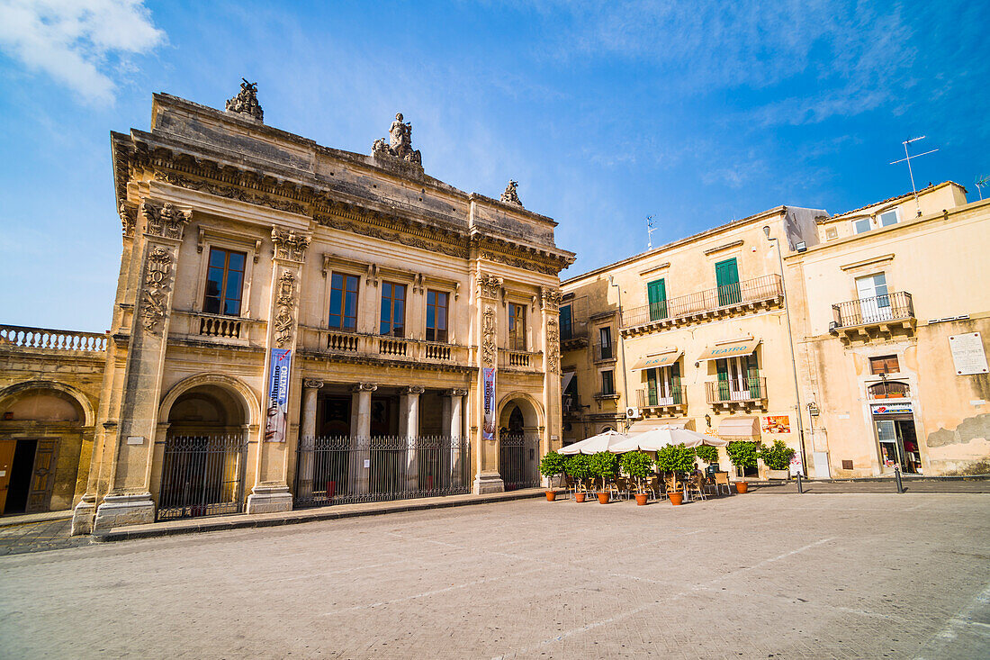 Theater von Noto (Teatro Comunale Vittorio Emanuele) und Caffe del Teatro auf der Piazza XVI Maggio, Val di Noto, UNESCO-Weltkulturerbe, Sizilien, Italien, Europa. Dies ist ein Foto des Theaters von Noto (Teatro Comunale Vittorio Emanuele) und des Caffe del Teatro in Noto, in einem Gebiet, das als Val di Noto bekannt ist und zum UNESCO-Welterbe in Sizilien, Italien, Europa gehört. Das Theater von Noto (Teatro Comunale Vittorio Emanuele) in Noto ist ein typisches Gebäude des sizilianischen Barockstils. Noto ist eine von acht Städten, die für ihre beeindruckende Barockarchitektur bekannt sind un