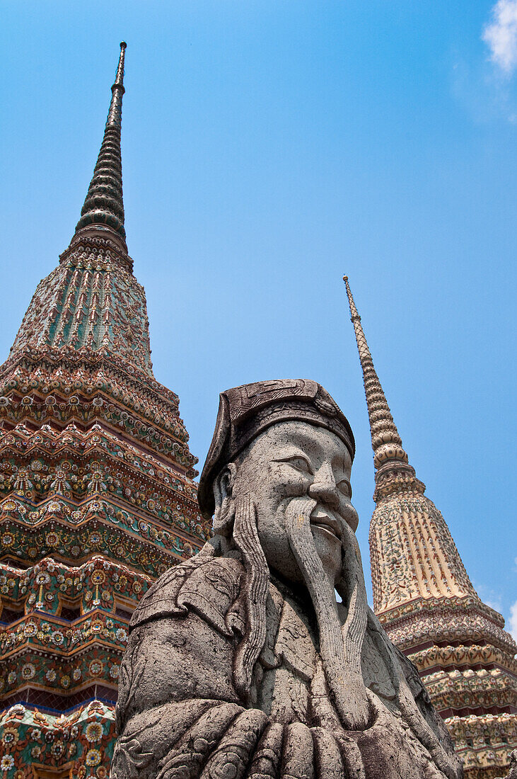 Steinwächterstatue und Tempeltürme (chedi) im Wat Pho, dem Tempel des liegenden Buddhas, dem größten buddhistischen Tempel in Bangkok, Thailand, und dem Geburtsort der Thai-Massage.