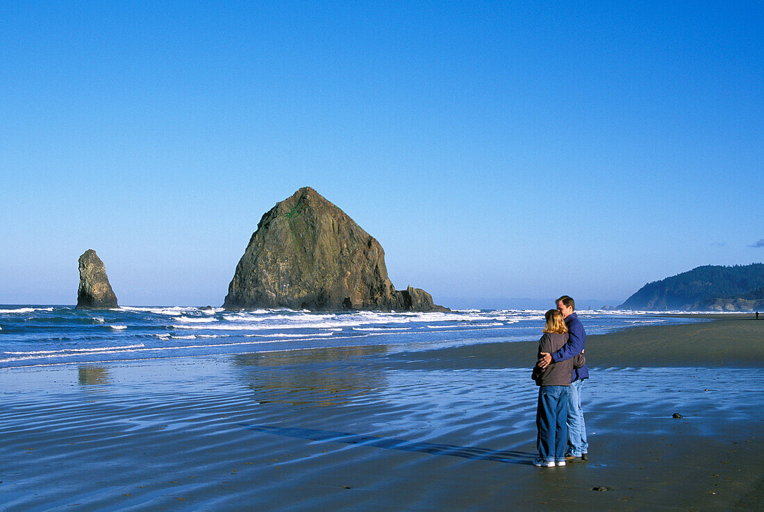 Paar am Strand und Haystack Rock; Cannon Beach, Nordküste von Oregon.