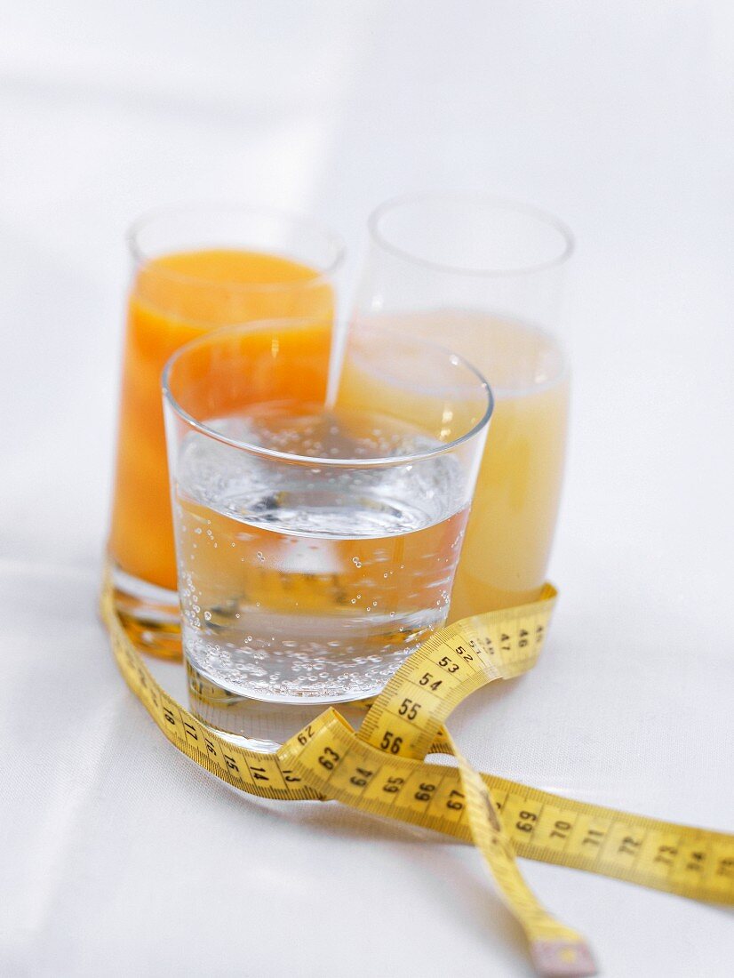 A glass of water & two glasses of juice, with tape measure