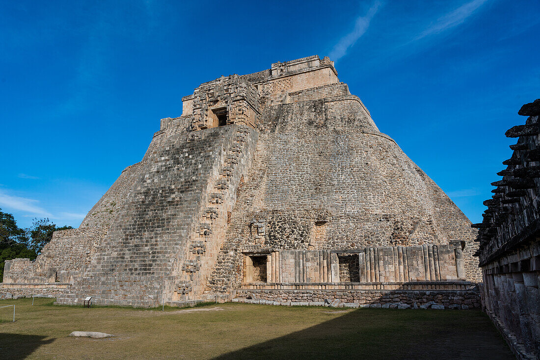 The west facade of the Pyramid of the Magician, also known as the Pyramid of the Dwarf, faces into the Quadrangle of the Birds. It is the tallest structure in the pre-Hispanic Mayan ruins of Uxmal, Mexico, rising about 35 meters or 115 feet. The temple at the top of the stairs is built in the Chenes style, while the upper temple is Puuc style.