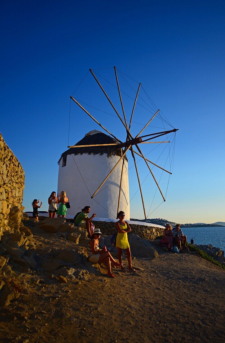 People enjoying sunset from traditional windmills (Kato Milli) in Mykonos town, Greece