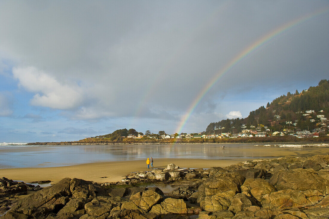 Doppelter Regenbogen über Yachats mit Menschen am Strand, Küste von Oregon.