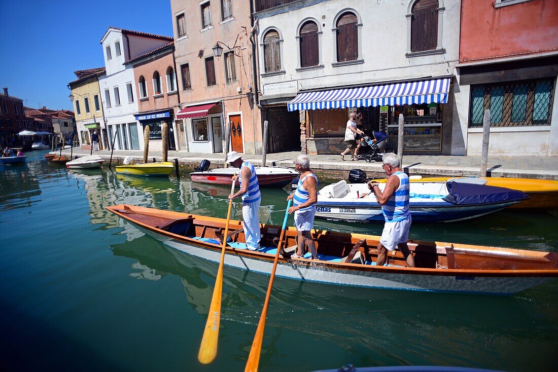 Gruppe reifer Männer auf einer Gondel in einem Kanal in Murano, Venedig, Italien