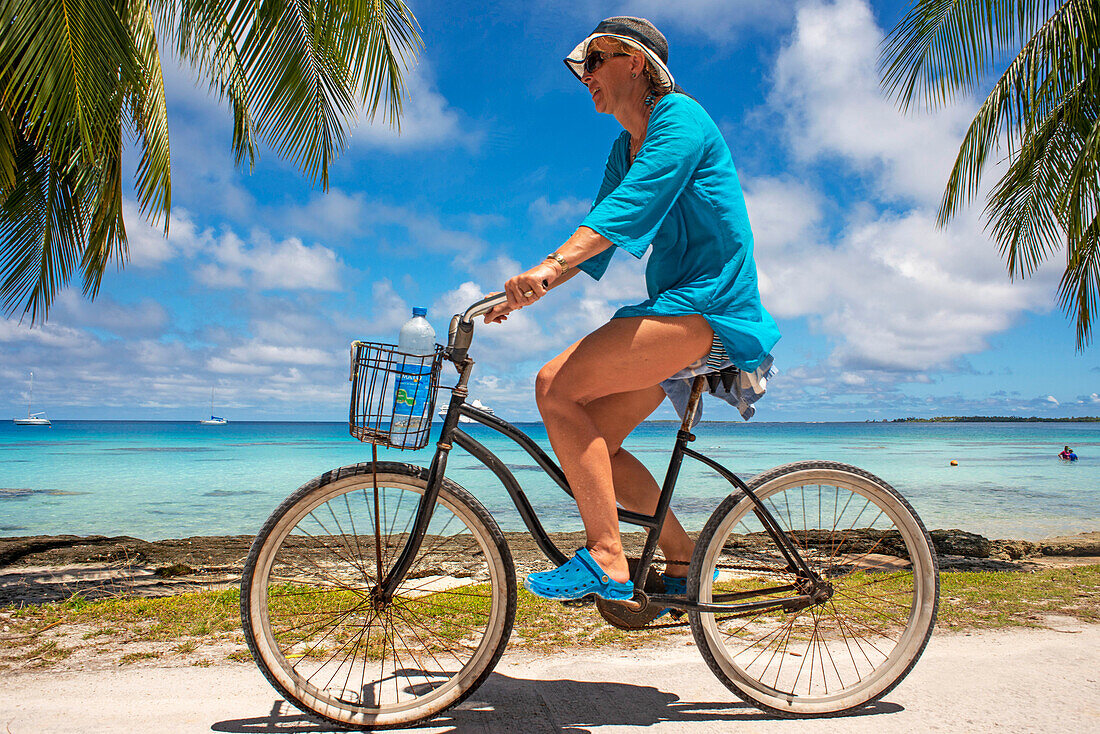 Touristenmädchen mit einem Fahrrad in Fakarava, Tuamotus-Archipel, Französisch-Polynesien, Tuamotu-Inseln, Südpazifik.