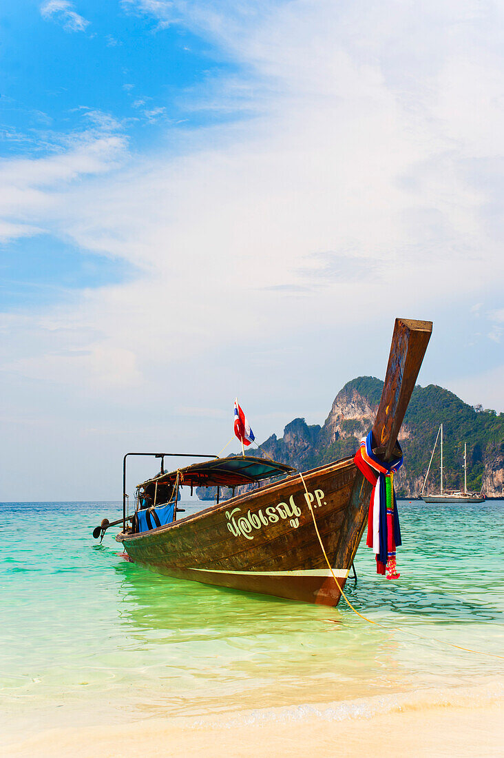A long tail boat moored up at a white sandy beach on Phi Phi Island, Thailand, South East Asia