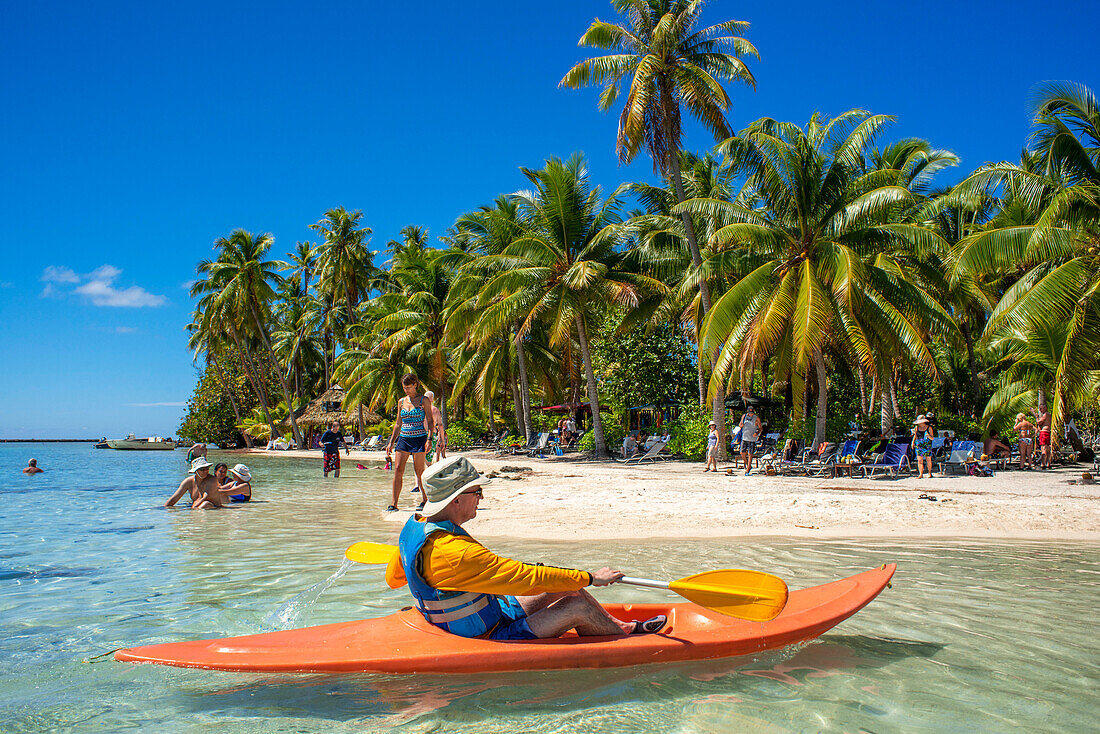 Kajakfahren am Strand der Insel Taha'a, Französisch-Polynesien. Motu Mahana Palmen am Strand, Taha'a, Gesellschaftsinseln, Französisch-Polynesien, Südpazifik.