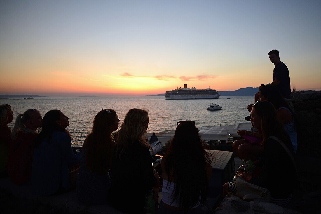 People enjoying views of Mykonos town at sunset, Greece