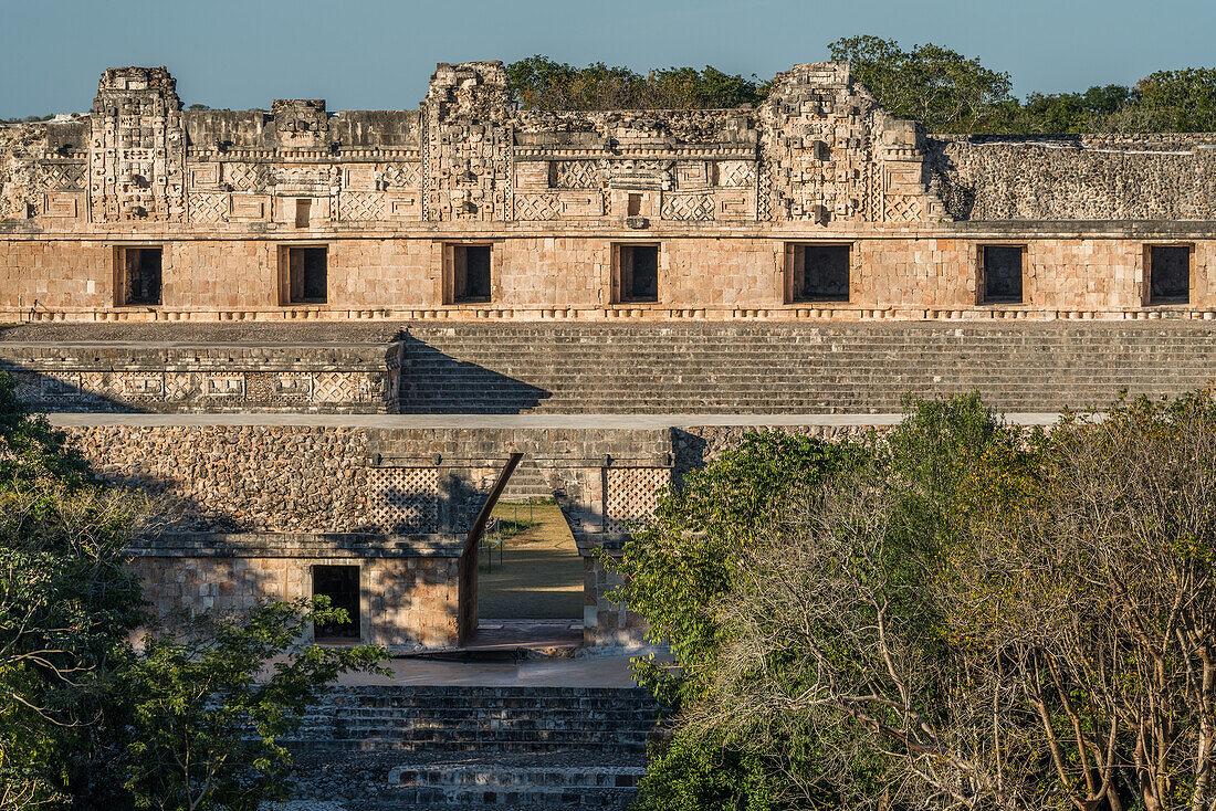 Das Nordgebäude des Nonnenklosters in den prähispanischen Maya-Ruinen von Uxmal, Mexiko. Im Vordergrund ist das Kragsteinportal des Südgebäudes des Quadrangels zu sehen.