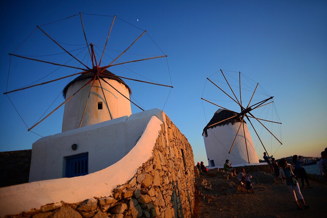 Menschen genießen den Sonnenuntergang von traditionellen Windmühlen (Kato Milli) in Mykonos-Stadt, Griechenland