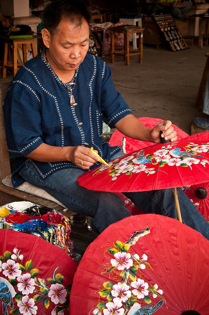 Mann bemalt Regenschirme in der Umbrella Factory in Chiang Mai, Thailand.