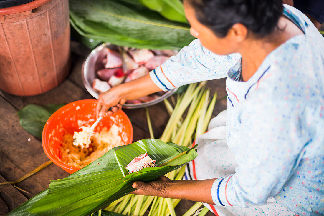 Woman preparing traditional dish of fish wrapped in banana leaves, Amazon Rainforest, Coca, Ecuador, South America