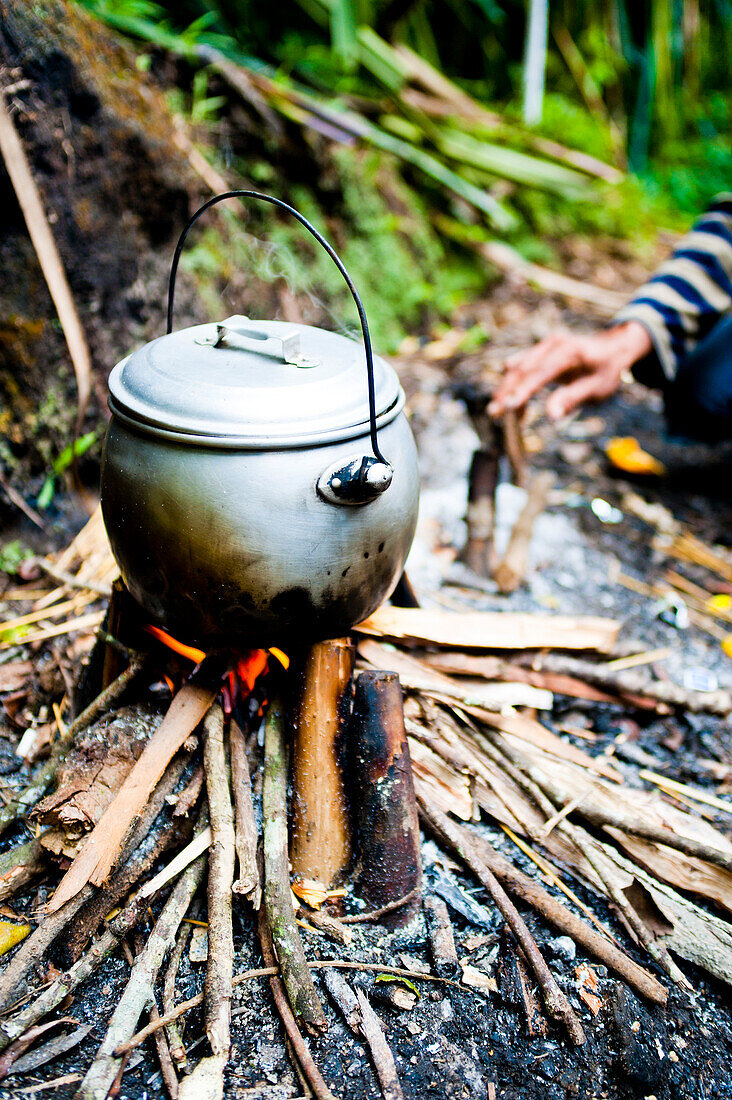 Tea Pot Boiling over the Camp Fire on the First Day of the Three Day Trek up Mount Rinjani, Lombok, Indonesia. The fact that your porter or guide prepare your lunch does make you feel a bit lazy, but a warm cup of sugary tea on arrival is always welcome! Mount Rinjani, (Gunung Rinjani in Indonesian) is an active volcano on Lombok island, Indonesia. Its summit of 3726m, makes it Indonesia's second highest volcano and provides impressive views over the entirety of the island of Lombok, and as far as to the west a Mount Agung and Mount Batur volcano on Bali, and as far the east as the island of S