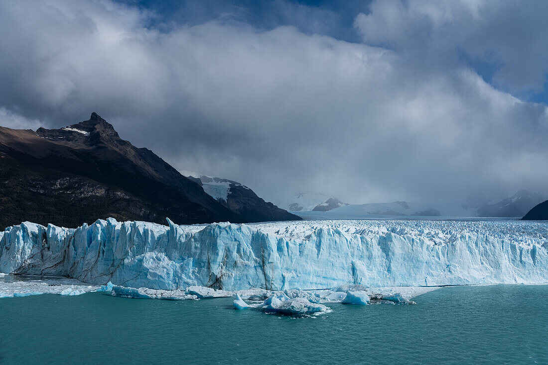 The jagged face of Perito Moreno Glacier and Lago Argentino in Los Glaciares National Park near El Calafate, Argentina. A UNESCO World Heritage Site in the Patagonia region of South America. Icebergs from calving ice from the glacier float in the lake. Behind at left is Cerro Moreno.