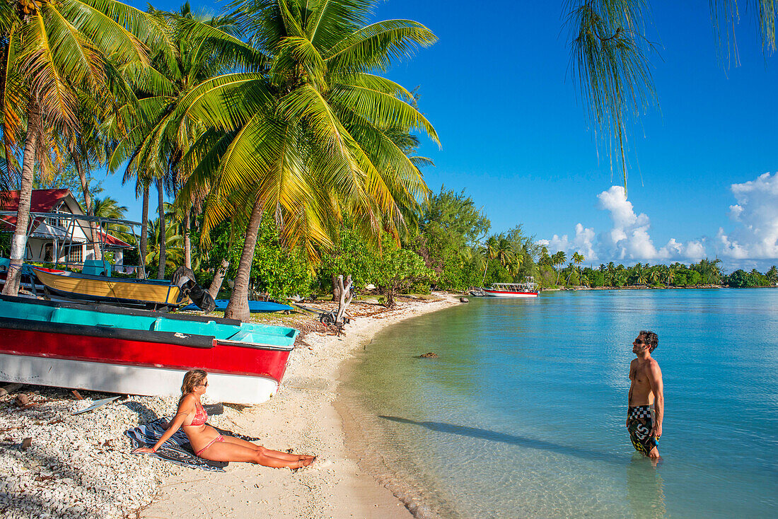 A couple relaxes in the beach of Rangiroa, Tuamotu Islands, French Polynesia, South Pacific.