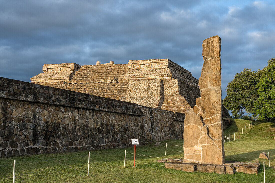 Stele 18 und die Pyramiden der Gruppe IV bei Sonnenaufgang in den präkolumbianischen zapotekischen Ruinen von Monte Alban in Oaxaca, Mexiko. Eine UNESCO-Welterbestätte.