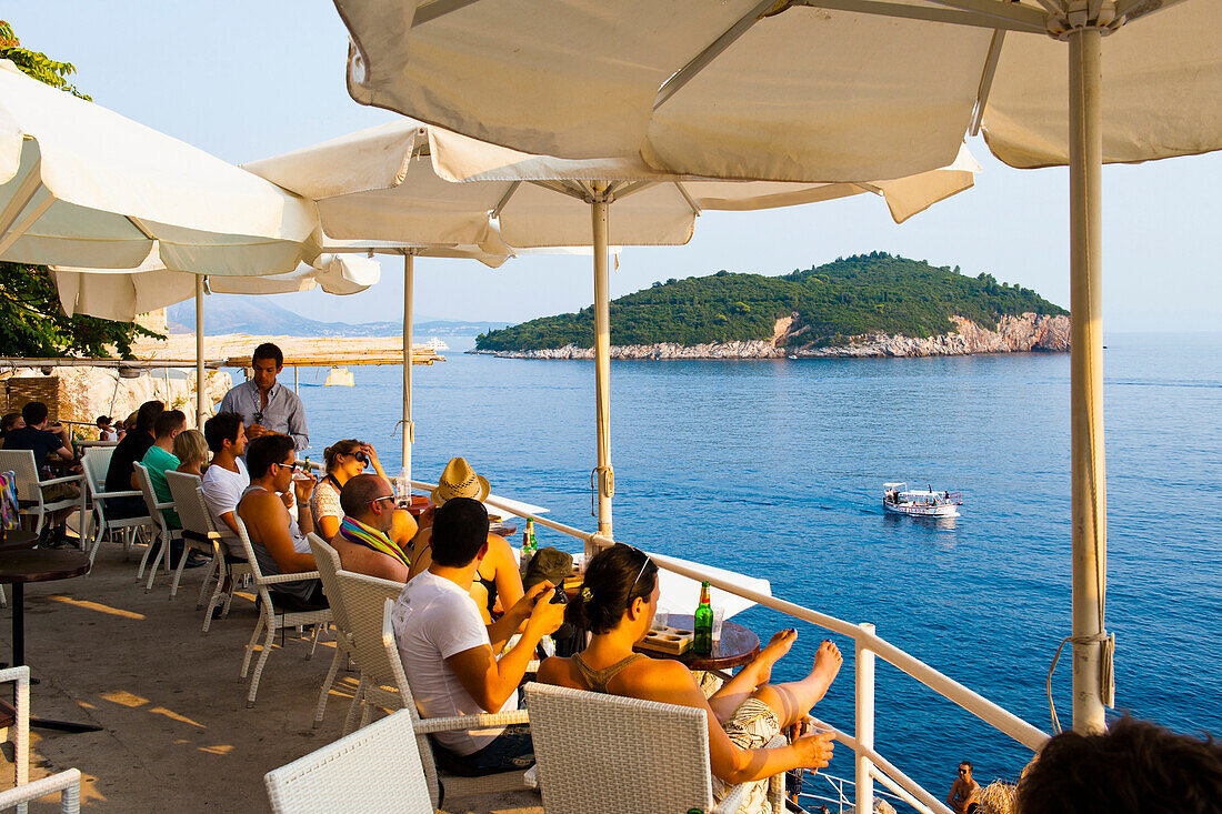 Cafe Buza, aka Buza Bar, Dubrovnik, Croatia. This is a photo of Buza Bar (Cafe Buza), a very popular bar in Dubrovnik. It is perched on a cliff and people can regularly be seen cliff jumping from the rocks at Buza Bar (Cafe Buza) into the beautiful blue Meditarranean Sea below. Directly opposite Buza Bar (Cafe Buza) is Lokrum Island, just off the Adriatic Coast of Dubrovnik, Croatia.