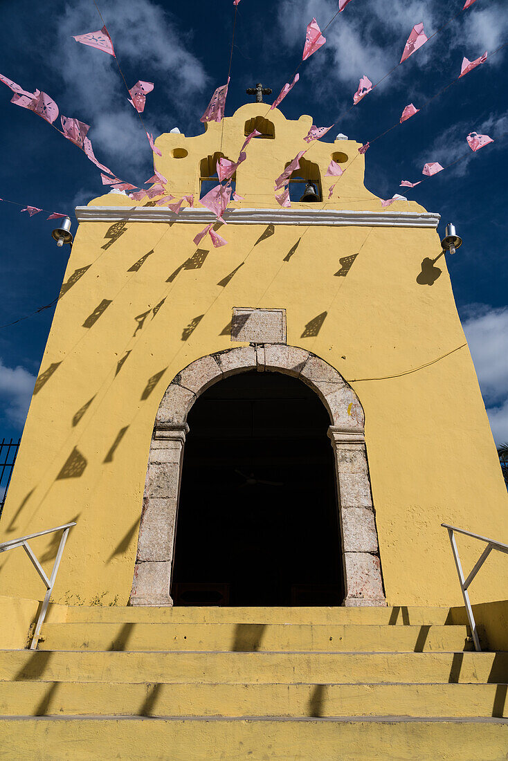 Banners over the small 16th Century colonial Chapel of Our Lady of Guadelupe in Acanceh, Yucatan, Mexico.