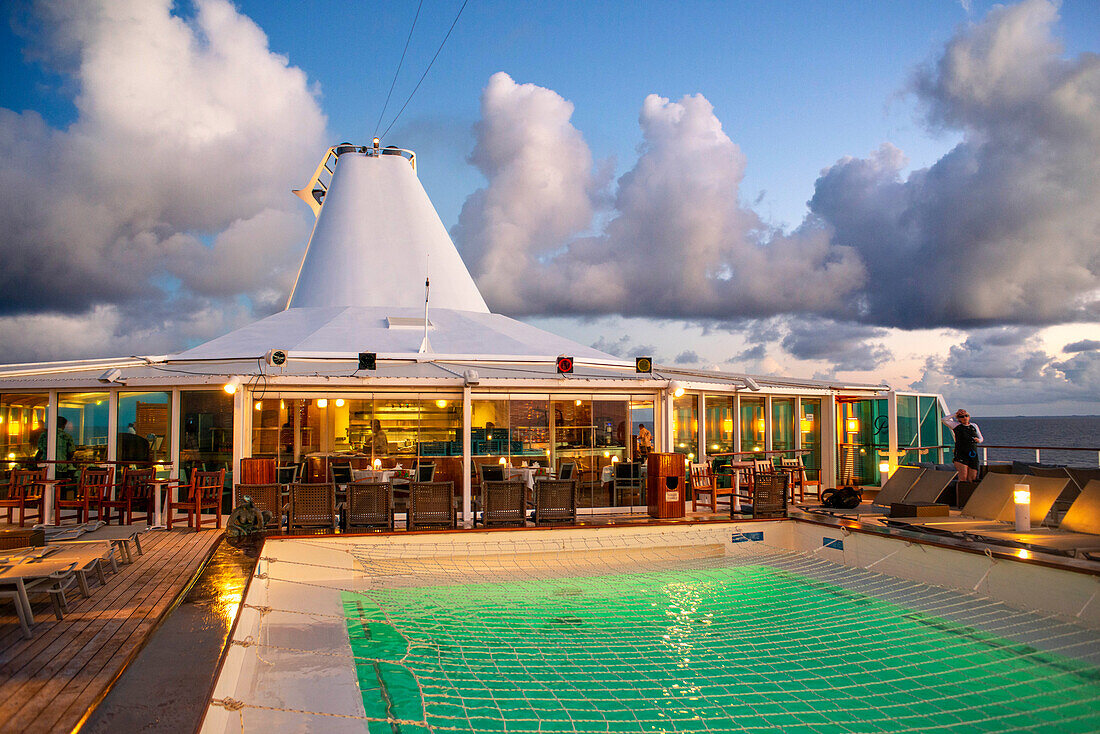 Paul Gauguin cruise ship, passengers relaxing in the upper deck in the swimming pool. Society Islands, French Polynesia, South Pacific.