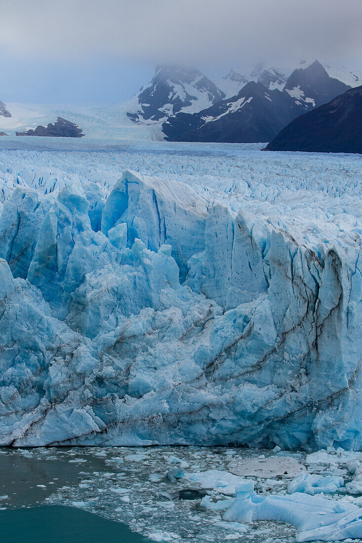 Die zerklüftete Wand des Perito-Moreno-Gletschers und der Lago Argentino im Los-Glaciares-Nationalpark in der Nähe von El Calafate, Argentinien. Ein UNESCO-Weltnaturerbe in der Region Patagonien in Südamerika. Eisberge vom kalbenden Eis des Gletschers schwimmen im See.