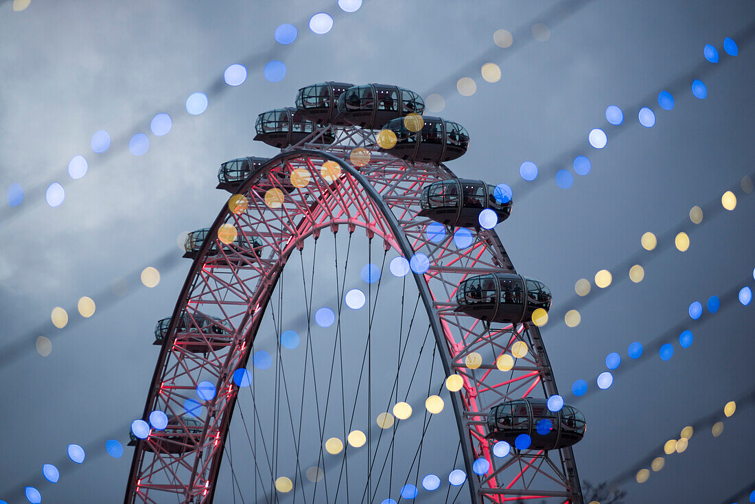 Das London Eye durch die nächtliche Weihnachtsbeleuchtung gesehen, South Bank, London, England