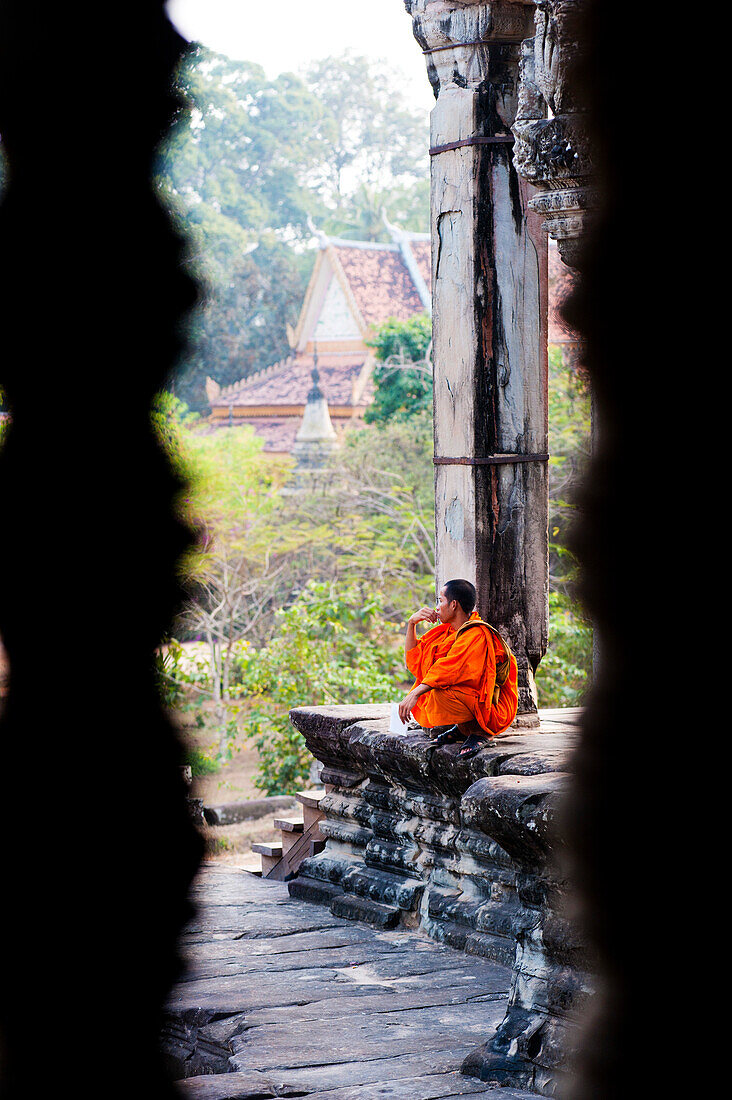 Buddhistischer Mönch beim Gebet in Angkor Wat, Kambodscha. Angkor Wat wurde im 12. Jahrhundert von Suryavarman II. erbaut. Obwohl Angkor Wat ursprünglich dem Hindu-Gott Vishnu geweiht war, ist es heute ein buddhistischer Tempel. Angkor Wat ist der berühmteste Tempel und steht daher bei den meisten Touristen ganz oben auf der Liste der "Muss-Sehenswürdigkeiten" und ist bei Sonnenaufgang und Sonnenuntergang extrem überlaufen. Es versteht sich von selbst, dass keine Reise zu den Angkor-Tempeln ohne einen Sonnenaufgang in Angkor Wat vollständig ist.