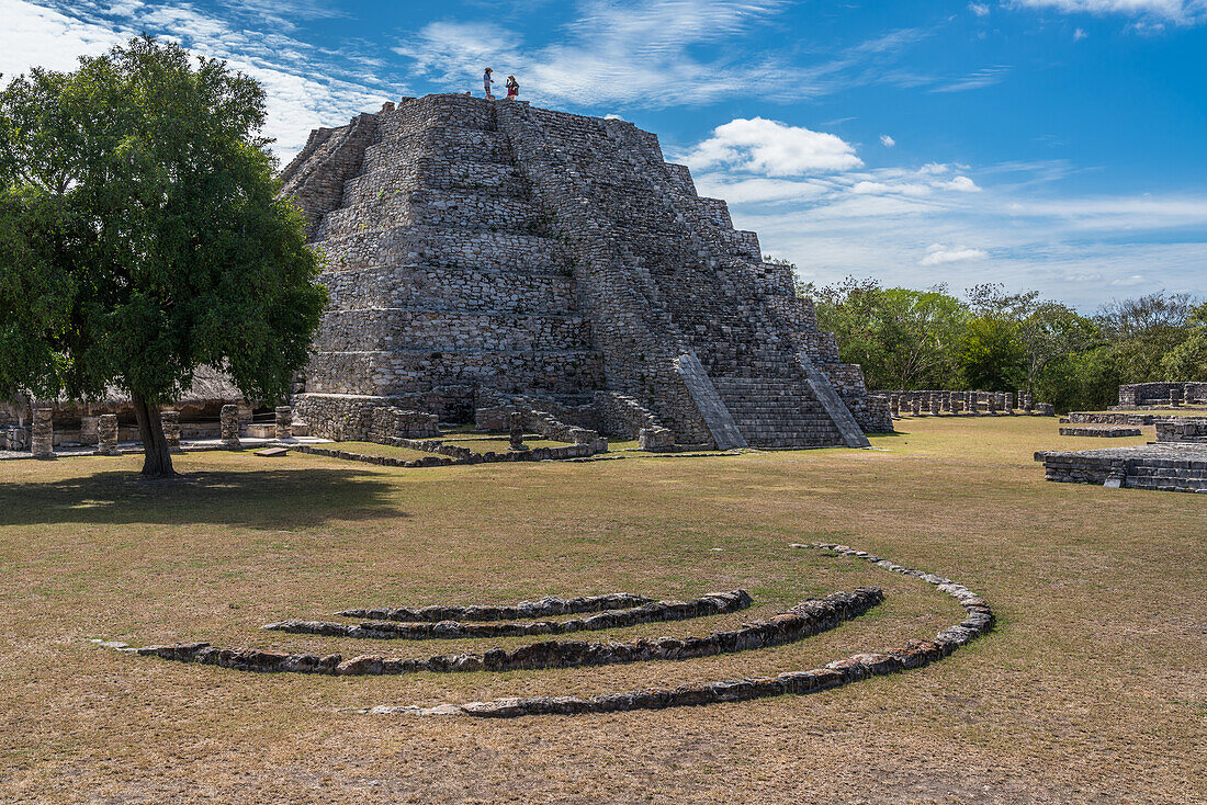 Tourist on top of the Pyramid of Kukulkan or the Castillo in the ruins of the Post-Classic Mayan city of Mayapan, Yucatan, Mexico.