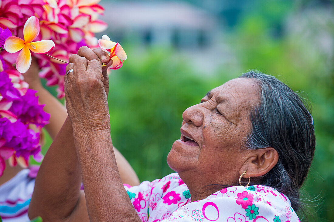A Salvadoran woman decorates palm fronds with flowers during the Flower & Palm Festival in Panchimalco, El Salvador