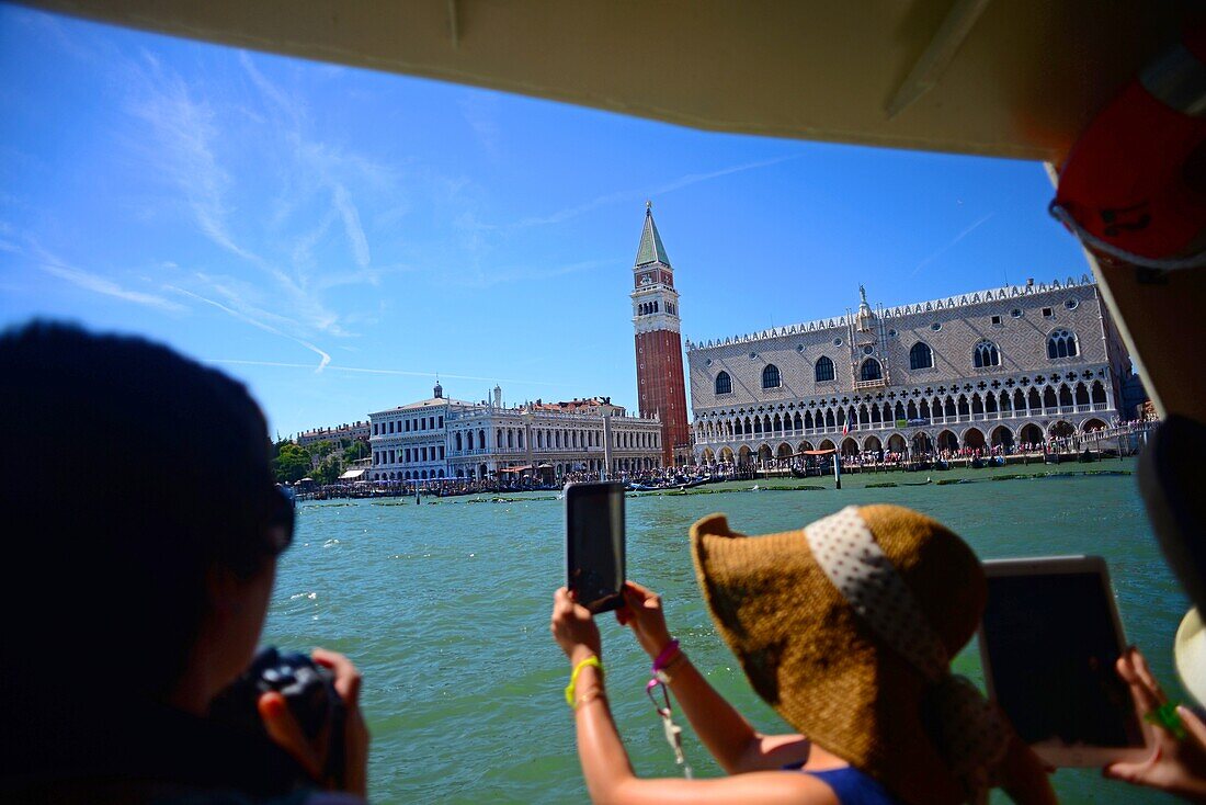 Tourists take photos from vaporetto, with Campanile di San Marco (St. Mark's bell tower) in view, Venice, Italy