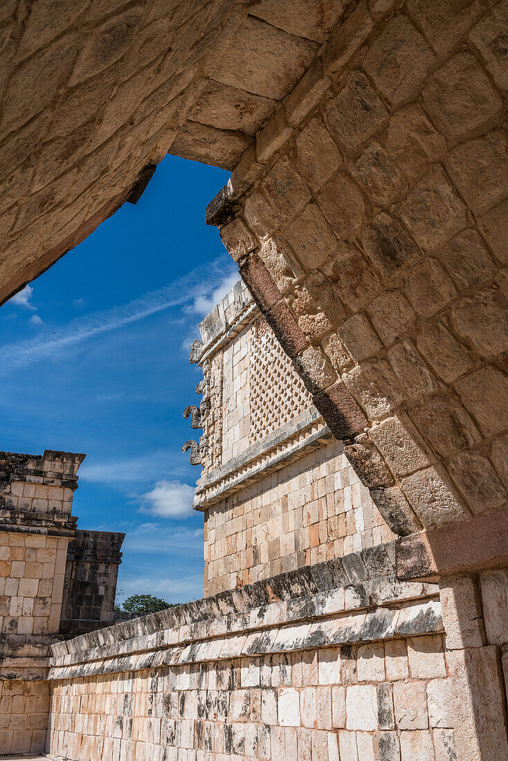 Der Blick durch einen Bogen im Viereck der Vögel in den Ruinen der Maya-Stadt Uxmal in Yucatan, Mexiko. Chaac-Masken schmücken die Ecke des Nonnenklosters. Die prähispanische Stadt Uxmal - ein UNESCO-Weltkulturerbe.