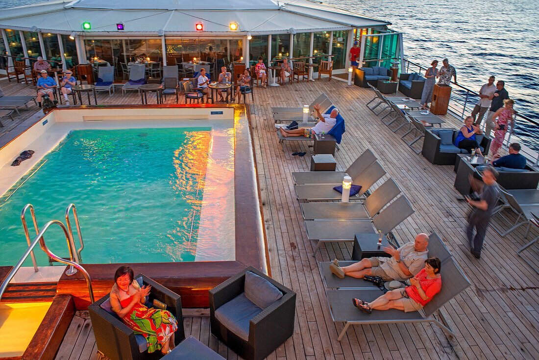 Paul Gauguin Kreuzfahrtschiff, Passagiere entspannen sich auf dem Oberdeck im Swimmingpool. Gesellschaftsinseln, Französisch-Polynesien, Südpazifik.