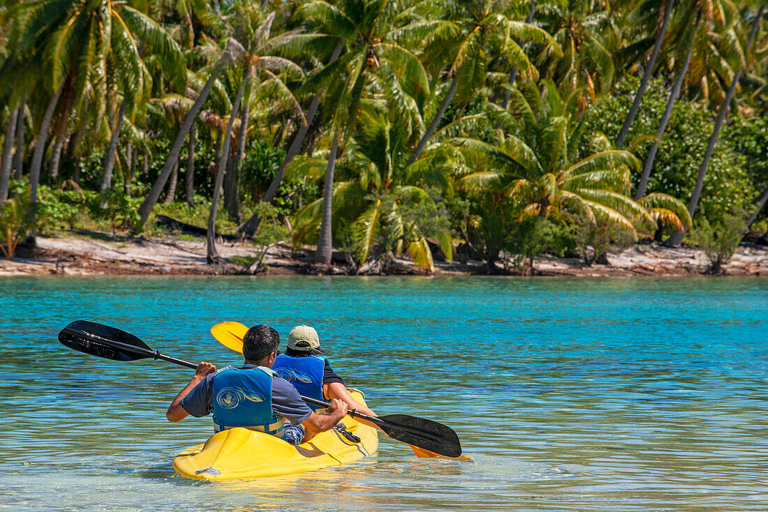 Kajakfahren am Strand der Insel Taha'a, Französisch-Polynesien. Motu Mahana Palmen am Strand, Taha'a, Gesellschaftsinseln, Französisch-Polynesien, Südpazifik.