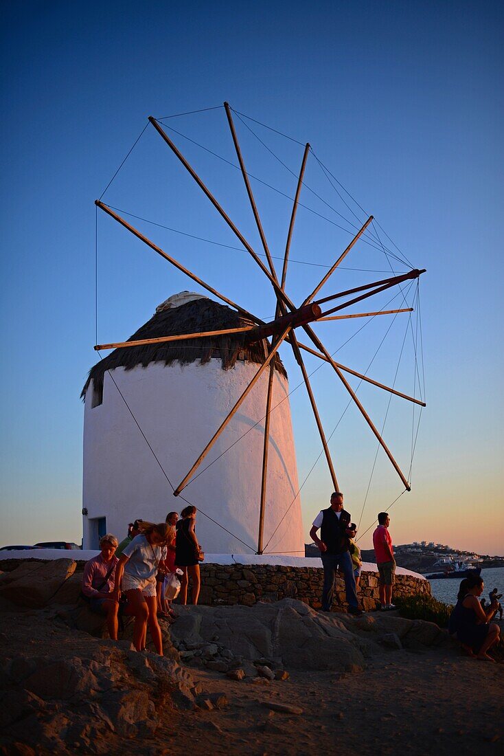 People enjoying sunset from traditional windmills (Kato Milli) in Mykonos town, Greece
